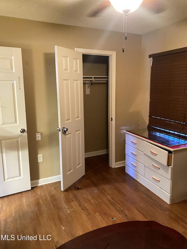 unfurnished bedroom with ceiling fan, a closet, and hardwood / wood-style floors