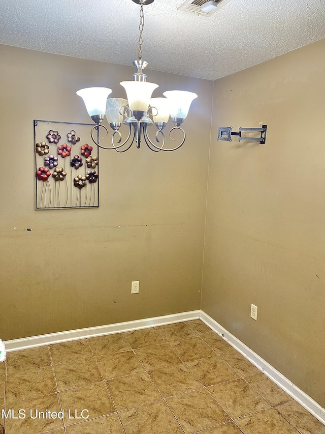 unfurnished dining area with a textured ceiling and a notable chandelier