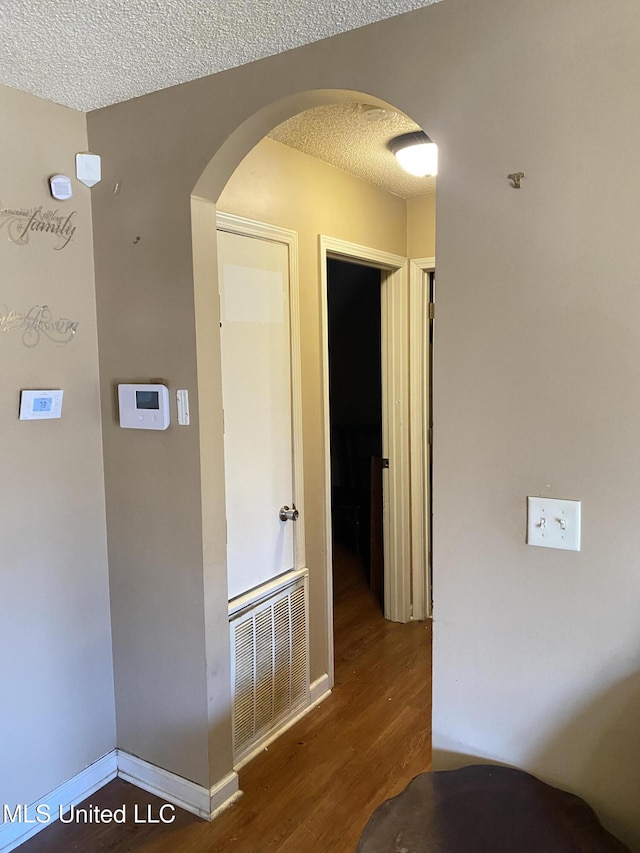 hall featuring a textured ceiling and dark wood-type flooring