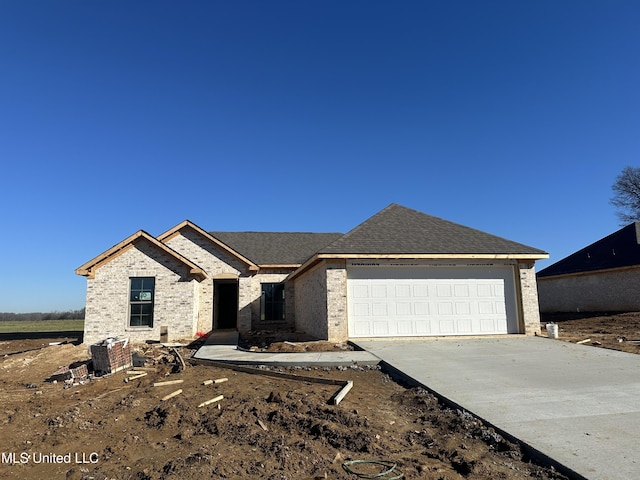 view of front of property featuring a shingled roof, concrete driveway, an attached garage, central AC, and brick siding