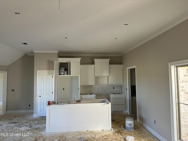 kitchen with crown molding, white cabinets, a kitchen island, and baseboards