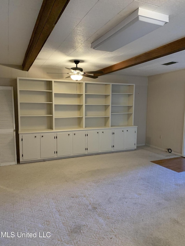 unfurnished living room featuring beamed ceiling, light carpet, a textured ceiling, and ceiling fan