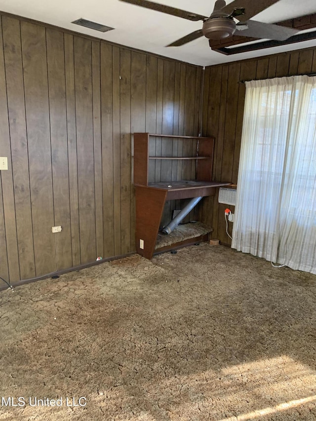 carpeted empty room featuring ceiling fan and wooden walls