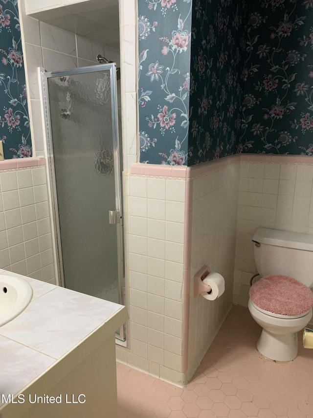 bathroom featuring vanity, tile patterned flooring, toilet, tile walls, and an enclosed shower