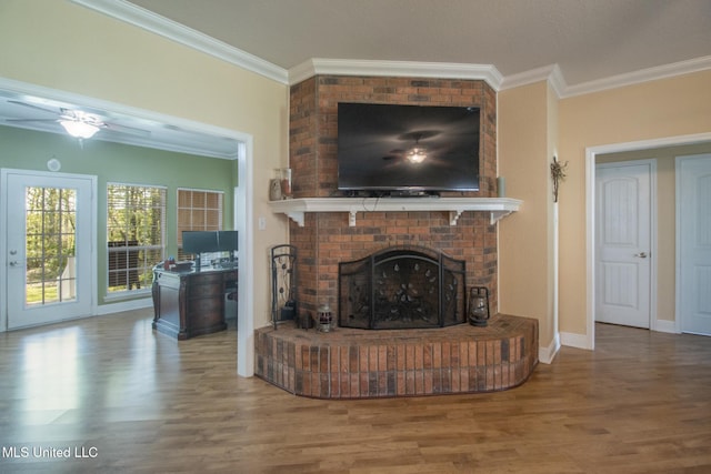 living room with hardwood / wood-style flooring, a brick fireplace, ceiling fan, and crown molding