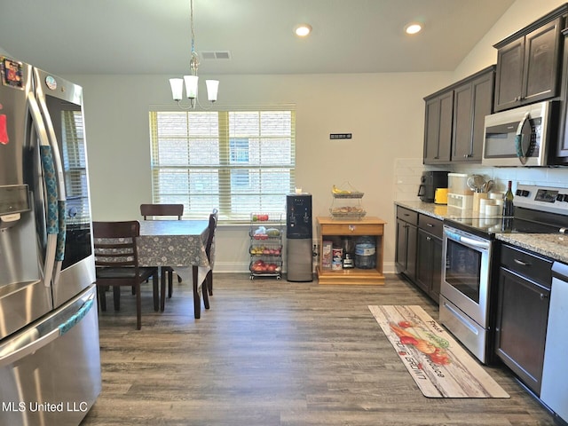 kitchen with dark brown cabinetry, light stone counters, dark hardwood / wood-style floors, a chandelier, and appliances with stainless steel finishes