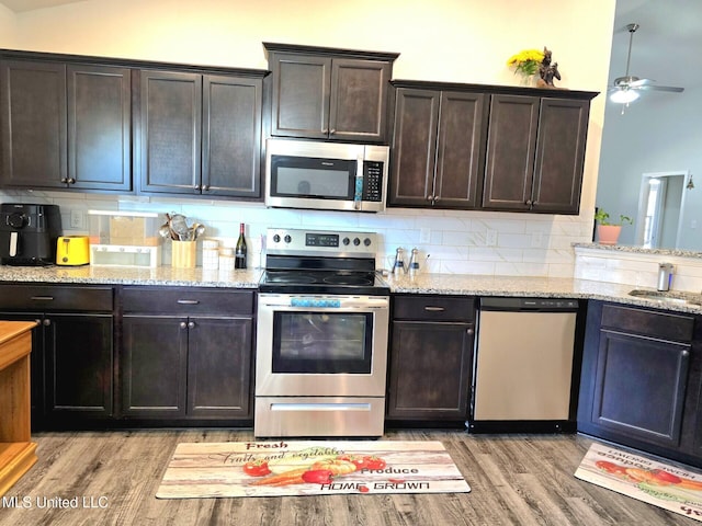 kitchen with dark brown cabinets, light wood-type flooring, appliances with stainless steel finishes, and tasteful backsplash