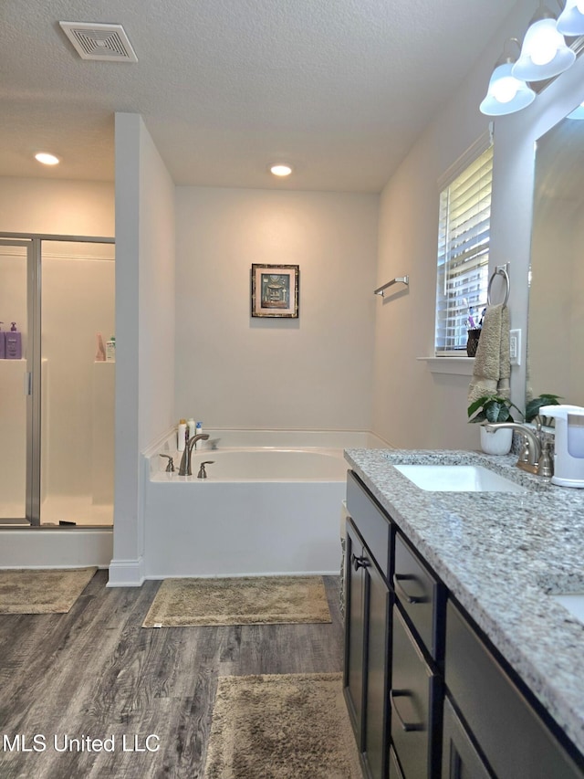 bathroom featuring hardwood / wood-style flooring, vanity, a textured ceiling, and plus walk in shower