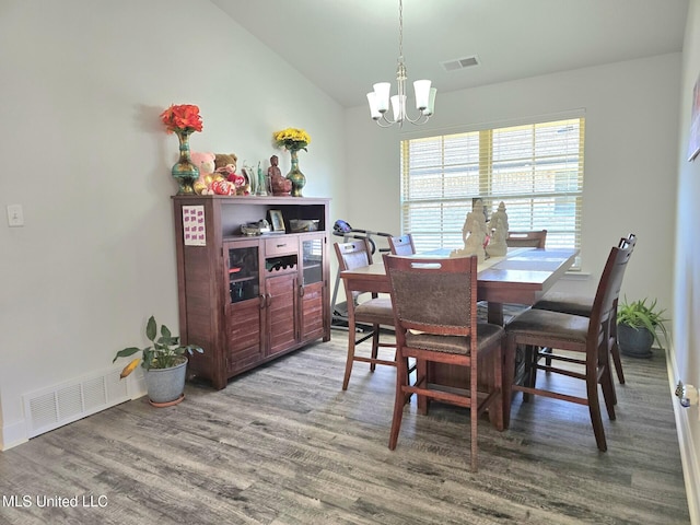 dining room with a chandelier, wood-type flooring, and vaulted ceiling