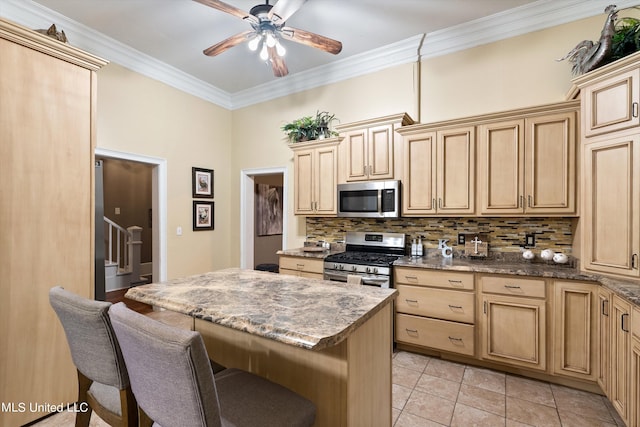 kitchen featuring a breakfast bar area, stainless steel appliances, backsplash, ornamental molding, and a center island