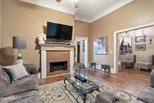 living room with ceiling fan, wood-type flooring, ornamental molding, and a brick fireplace