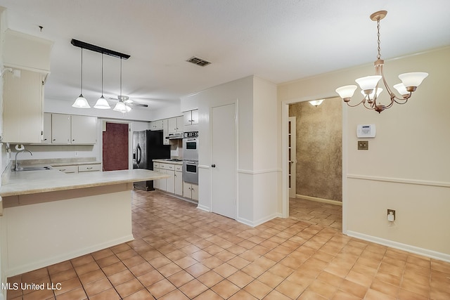 kitchen with sink, kitchen peninsula, stainless steel double oven, white cabinetry, and pendant lighting