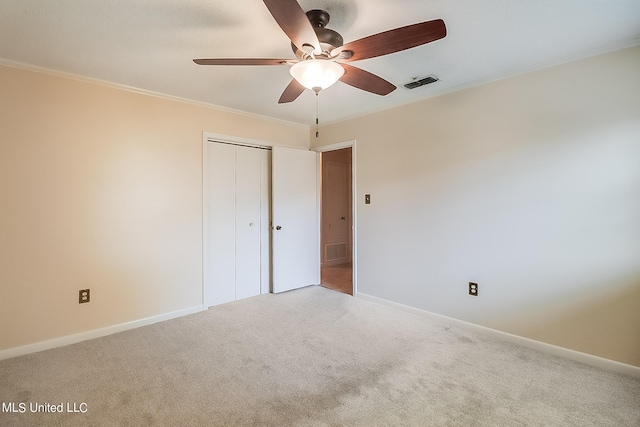 unfurnished bedroom with a closet, carpet floors, crown molding, and ceiling fan