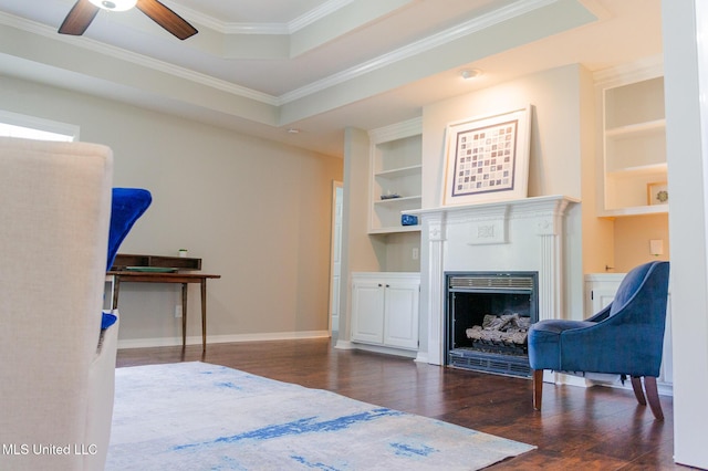 bedroom featuring wood finished floors, crown molding, a fireplace, a raised ceiling, and baseboards