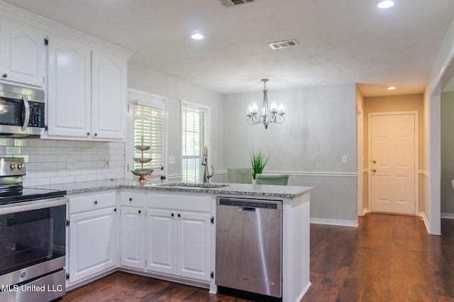 kitchen with appliances with stainless steel finishes, a peninsula, a sink, recessed lighting, and tasteful backsplash