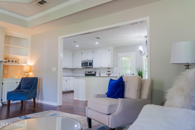 living area with dark wood-style floors, ornamental molding, a chandelier, and recessed lighting