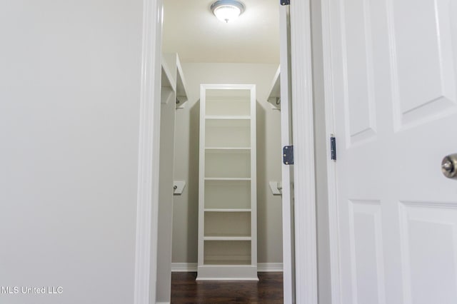 corridor featuring dark wood-type flooring and baseboards
