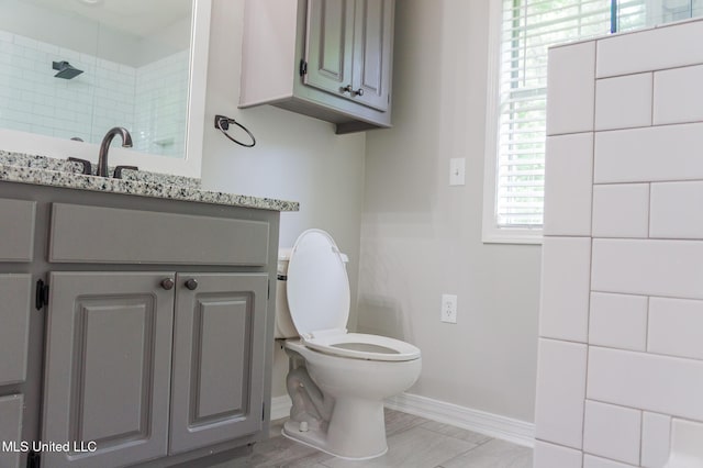 full bathroom featuring baseboards, toilet, vanity, and a shower