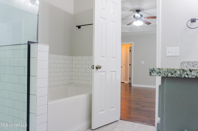 bathroom with ceiling fan, a garden tub, and baseboards