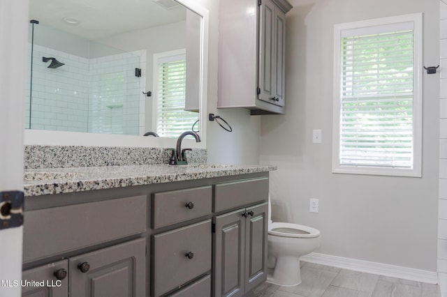 bathroom with a shower stall, toilet, vanity, and baseboards