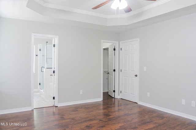 unfurnished bedroom featuring ornamental molding, wood finished floors, a walk in closet, baseboards, and connected bathroom