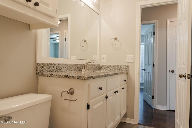 bathroom featuring vanity, a ceiling fan, toilet, and baseboards