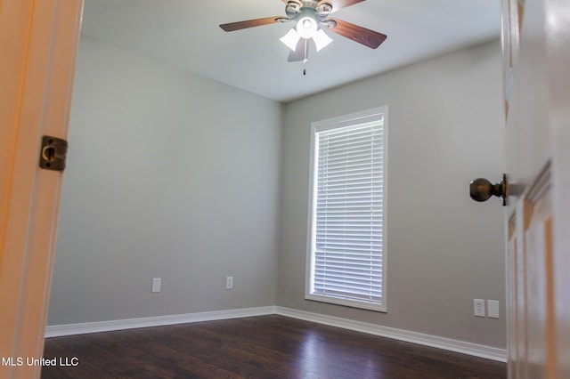 empty room featuring a ceiling fan, dark wood-style flooring, baseboards, and plenty of natural light