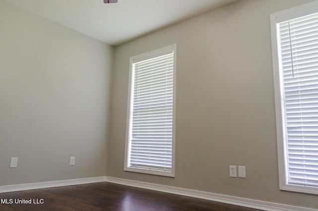 spare room featuring dark wood finished floors and baseboards