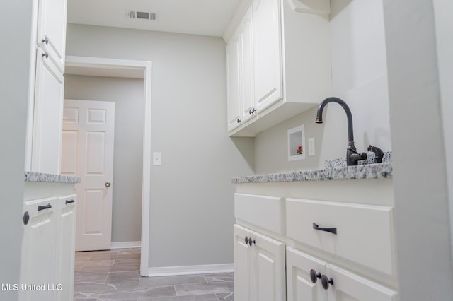 clothes washing area with cabinet space, washer hookup, and baseboards