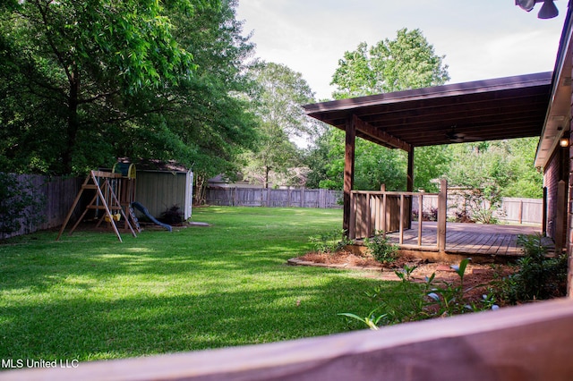 view of yard with a ceiling fan, a deck, and a playground