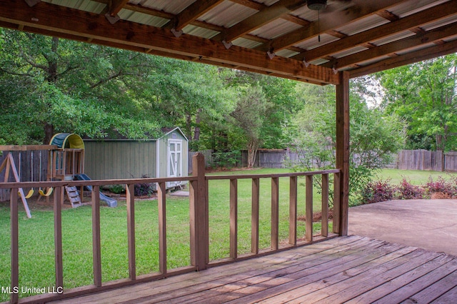 wooden deck featuring a storage shed, a playground, and an outbuilding