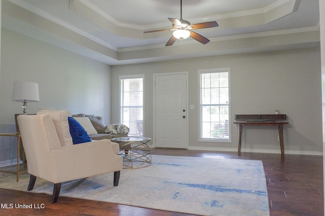foyer with a tray ceiling, ornamental molding, wood finished floors, ceiling fan, and baseboards