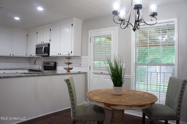 kitchen with appliances with stainless steel finishes, a chandelier, white cabinetry, backsplash, and light stone countertops