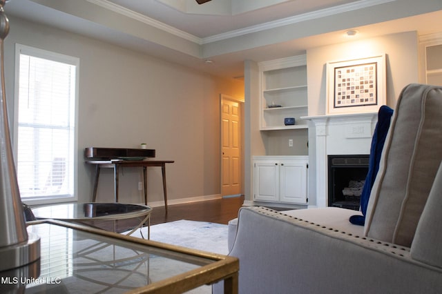 living area featuring ornamental molding, healthy amount of natural light, a fireplace, baseboards, and built in shelves