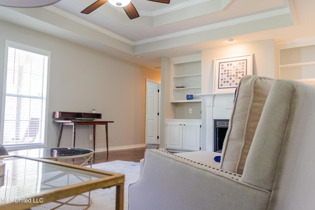 office area featuring healthy amount of natural light, built in features, crown molding, ceiling fan, and a tray ceiling