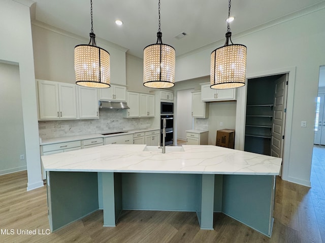 9549 Mcelroy Farms Dr, Olive Branch, MS 38654 - kitchen with under cabinet range hood, cooktop, tasteful backsplash, a chandelier, and ornamental molding