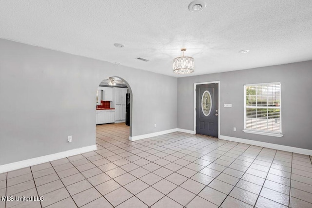 1320 Sally Dr, Picayune, MS 39466 - entrance foyer with a chandelier, a textured ceiling, light tile patterned floors, arched walkways, and baseboards