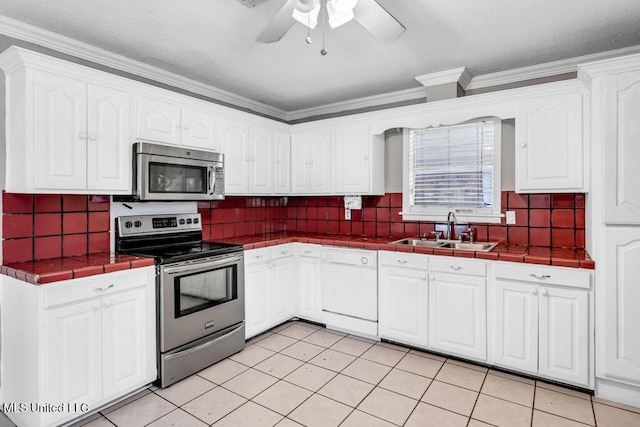 1320 Sally Dr, Picayune, MS 39466 - kitchen with stainless steel appliances, a sink, tile countertops, white cabinets, and crown molding