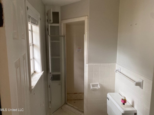 bathroom featuring toilet, a healthy amount of sunlight, and tile walls