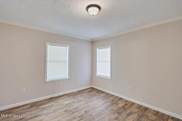 spare room featuring crown molding, wood-type flooring, and a textured ceiling