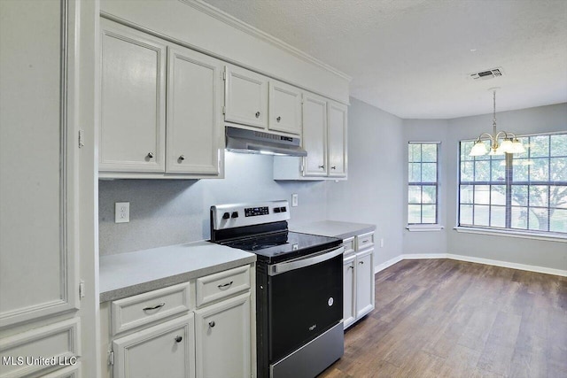 kitchen with stainless steel electric stove, visible vents, under cabinet range hood, an inviting chandelier, and light countertops