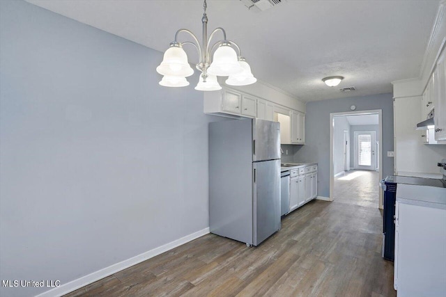 kitchen with freestanding refrigerator, a notable chandelier, white cabinetry, and under cabinet range hood