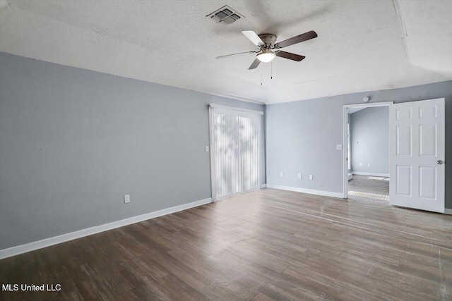 empty room with ceiling fan, a textured ceiling, baseboards, and wood finished floors