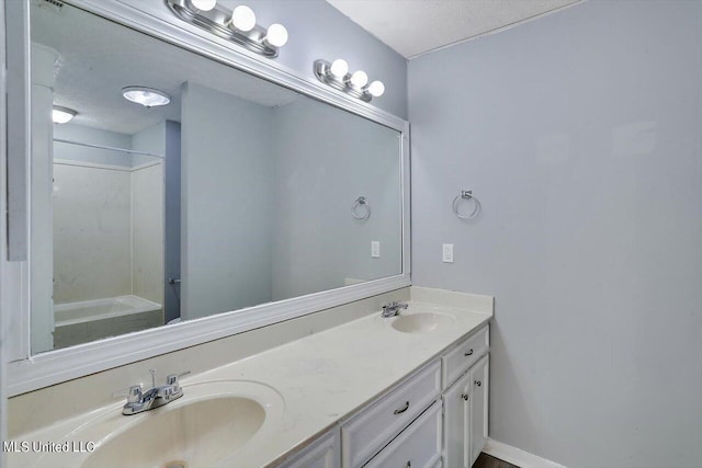 bathroom featuring a textured ceiling, double vanity, and a sink