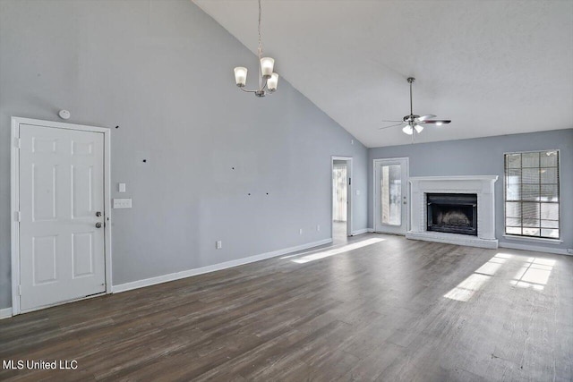 unfurnished living room with a brick fireplace, ceiling fan with notable chandelier, high vaulted ceiling, and plenty of natural light