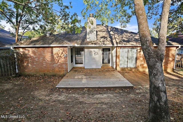rear view of property with a chimney, roof with shingles, a wooden deck, and brick siding