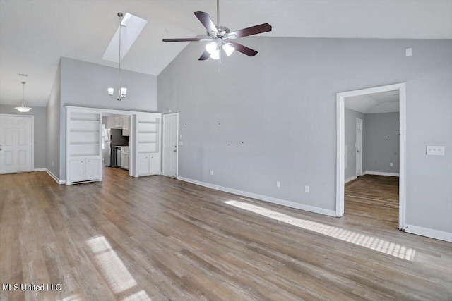 unfurnished living room featuring a skylight, wood finished floors, high vaulted ceiling, a ceiling fan, and baseboards