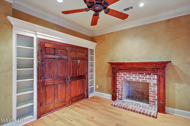 foyer entrance with a fireplace, ornamental molding, light hardwood / wood-style floors, and ceiling fan