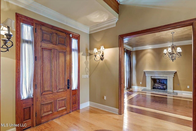 entrance foyer with light wood-type flooring, crown molding, and a notable chandelier