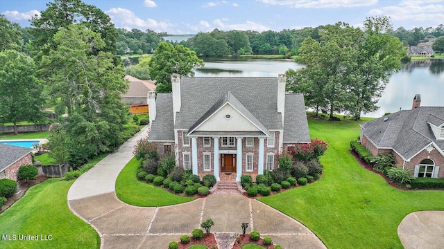 view of front of home with a front lawn and a water view